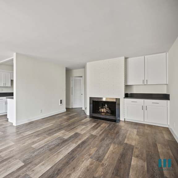 open-concept dining and living room with fireplace, built-in cabinets, and vinyl flooring