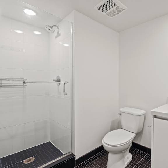 bathroom with stand-up shower with glass door and vanity cabinet storage