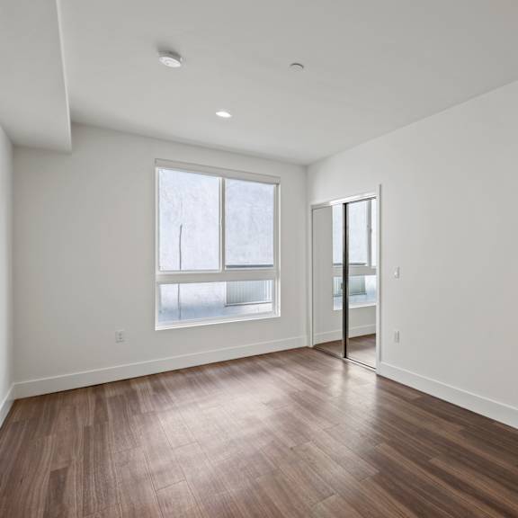 bedroom with a mirrored closet, vinyl flooring, and windows