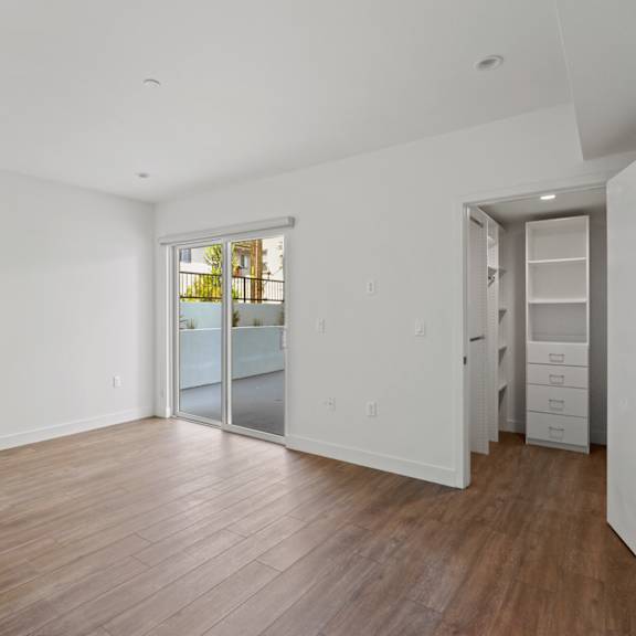 bedroom with walk-in closet with built-in organizers, vinyl flooring, and patio