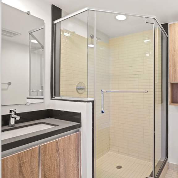 bathroom with stand-up shower with glass door and cabinet storage