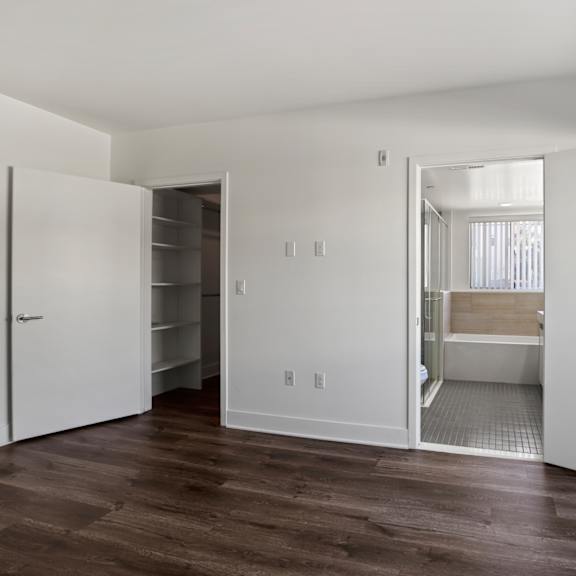 bedroom, walk-in closet with shelving, bathroom, and balcony