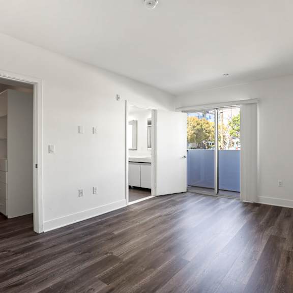 bedroom with walk-in closet, vinyl flooring, and  balcony