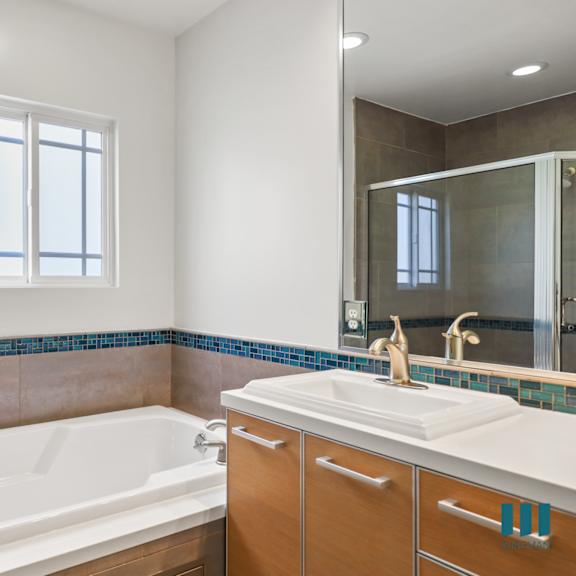 bathroom with full-size bathtub, walk-in shower, and vanity cabinet storage