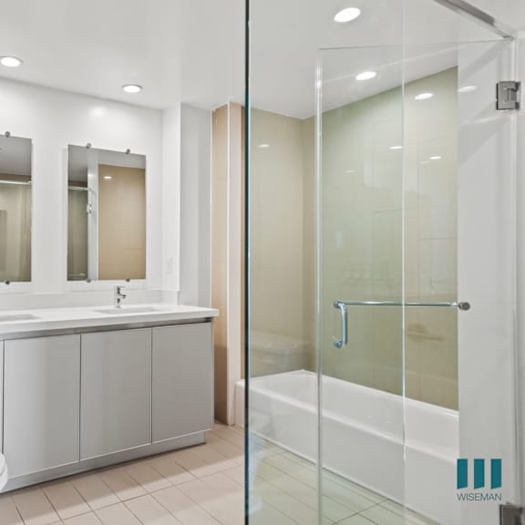 bathroom with walk-in shower, bathtub, and double-sink vanity with cabinet storage