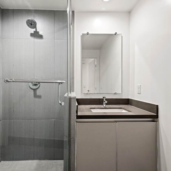 bathroom with a stand-up shower with glass door and cabinet storage