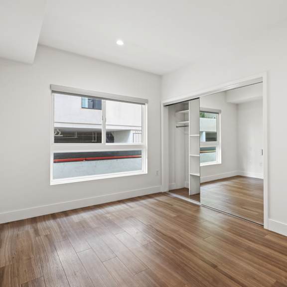 bedroom with mirrored closet with shelving, large windows, and vinyl flooring