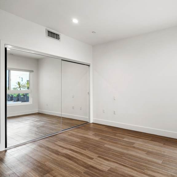bedroom with mirrored closet, large windows, and vinyl flooring