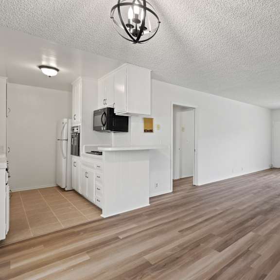 a spacious living room with wooden flooring and white walls.