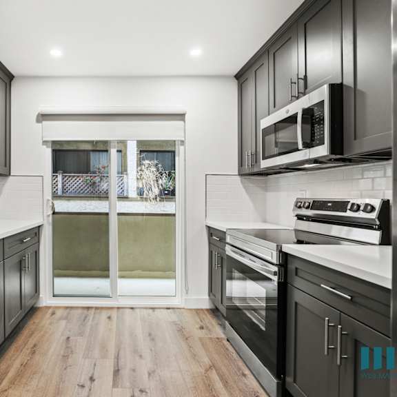 a modern kitchen with dark wood cabinets and stainless steel appliances.