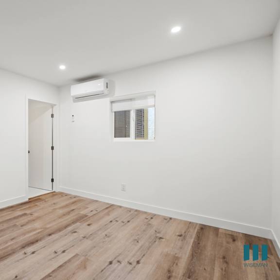 a room with wooden flooring and a window with blinds.