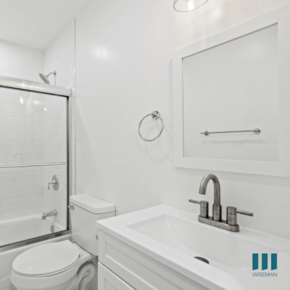 a white bathroom with a toilet, sink, and shower.