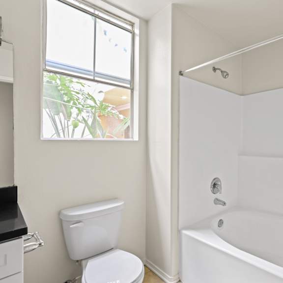 bathroom with window, bathtub, and cabinet storage