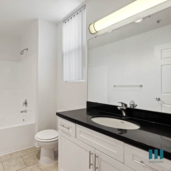 bathroom with full-size bathtub, vanity cabinet storage, and window