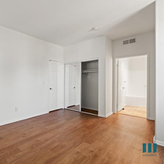 bedroom with bathroom, closet, and vinyl flooring