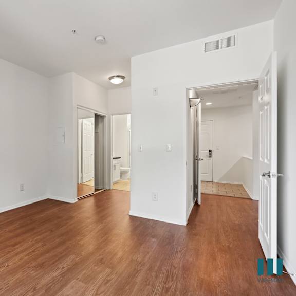 bedroom with bathroom, mirrored closet, and vinyl flooring