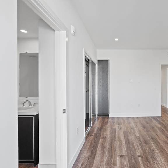 bedroom with closet, vinyl flooring, recessed lighting, and bathroom