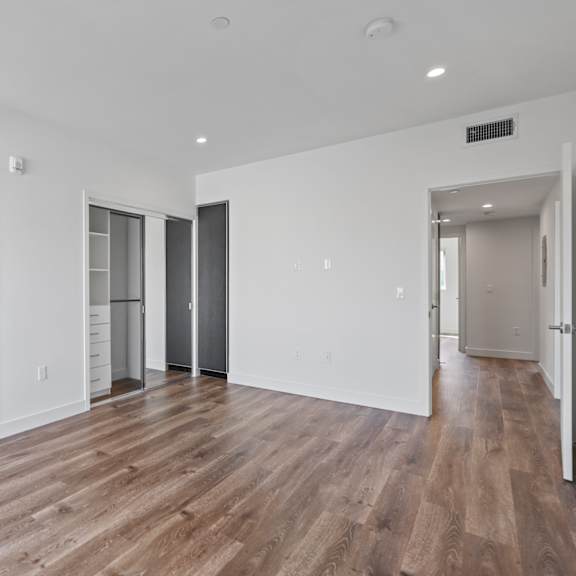 spacious bedroom with closet with organizers, recessed lighting, vinyl flooring, and bathroom