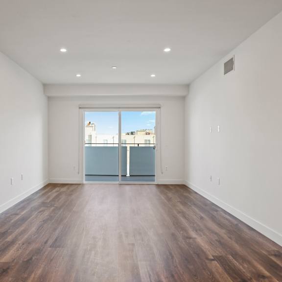 a bedroom with hardwood floors and white walls