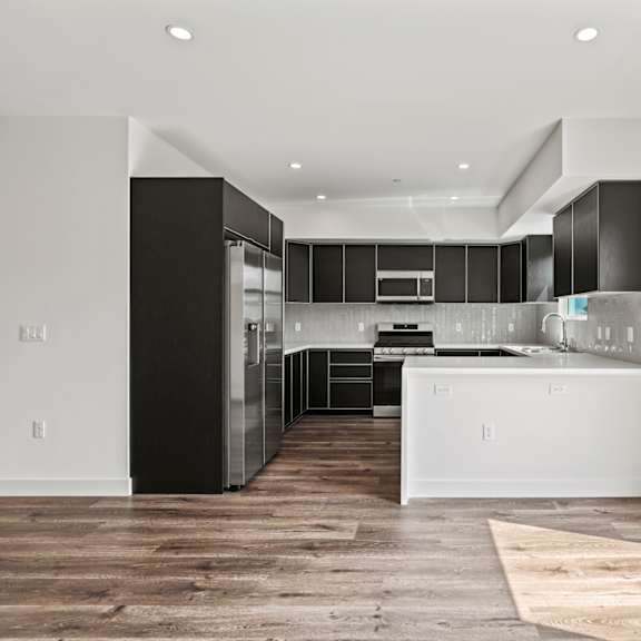 a kitchen with black and white cabinetry and a wooden floor