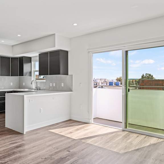 a kitchen and living room with a sliding glass door that leads to a balcony