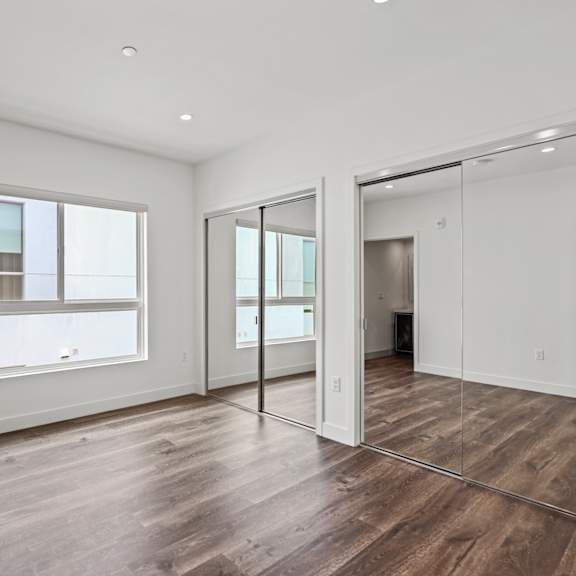 a bedroom with hardwood floors and white walls