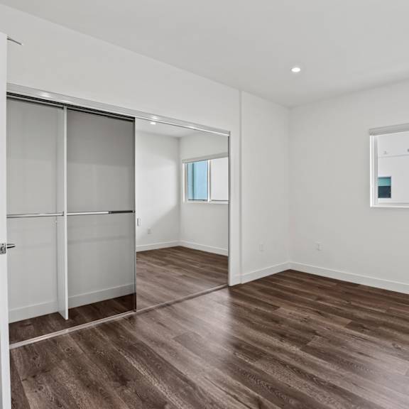 a bedroom with white walls and hardwood floors
