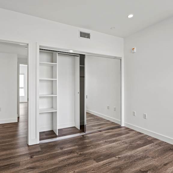 a bedroom with hardwood floors and white walls