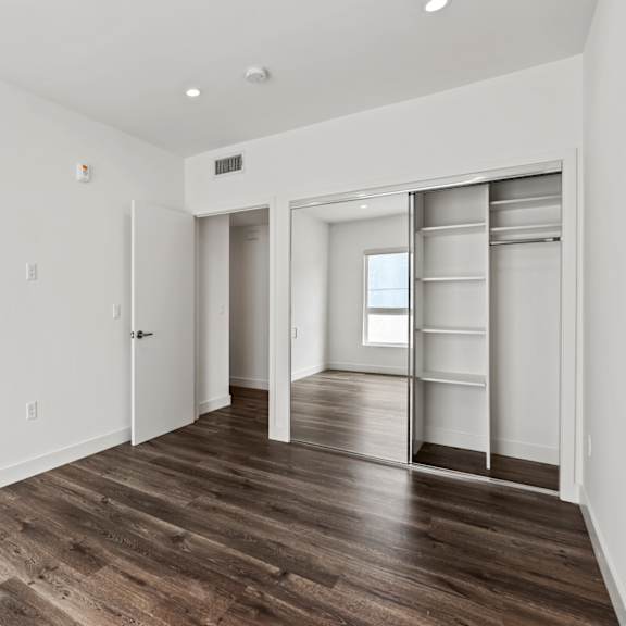 a bedroom with hardwood floors and white walls