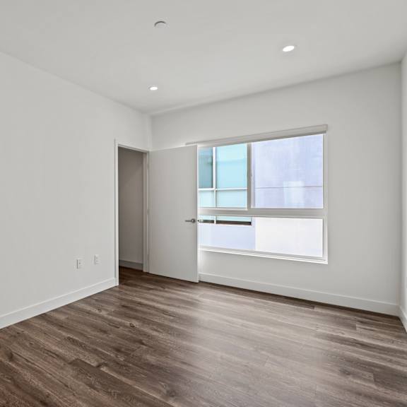 a bedroom with hardwood floors and white walls