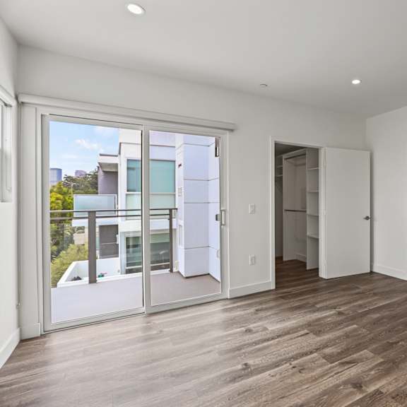 a bedroom with hardwood floors and white walls