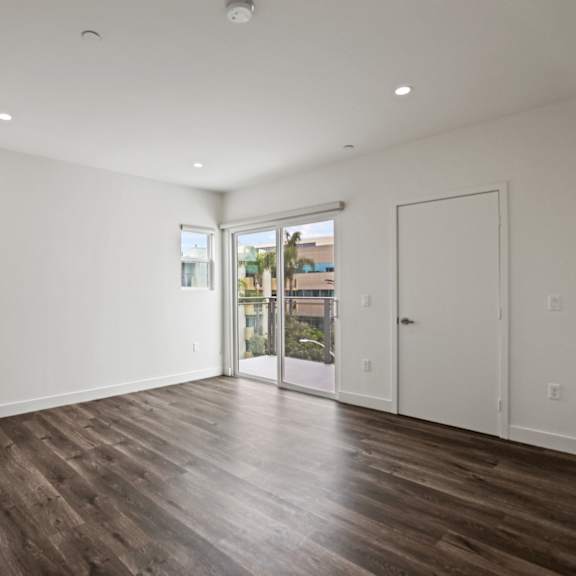 a bedroom with hardwood floors and white walls