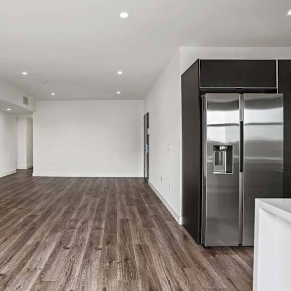 a kitchen and living room with white walls and a wooden floor