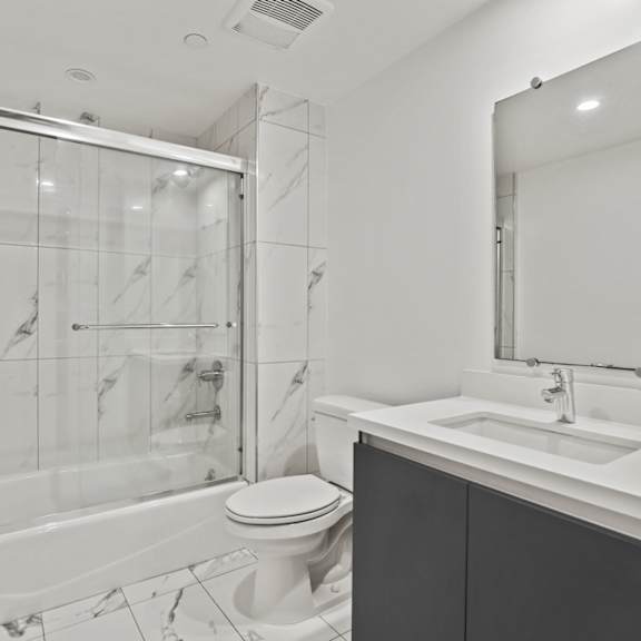 bathroom with shower bath with glass doors and vaniity cabinet storage