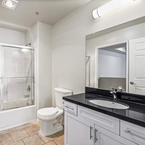 large-size bathroom with bathtub with a glass door and cabinet storage
