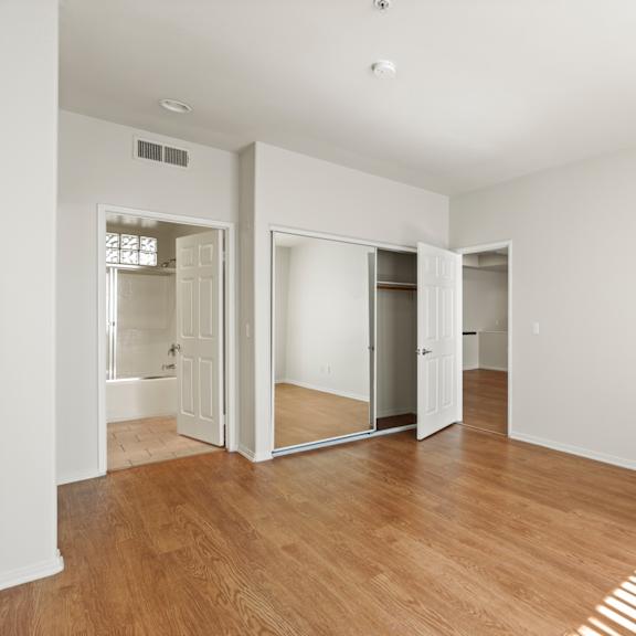 bedroom with two closets, bathroom, and vinyl flooring