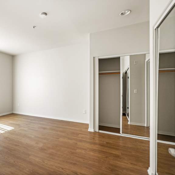 spacious bedroom with mirrored closet, window, and vinyl flooring