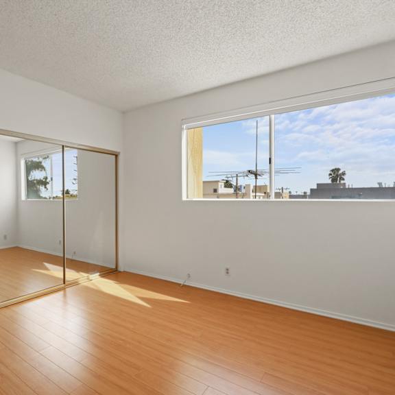 bedroom with large mirrored closet, vinyl flooring, and windows