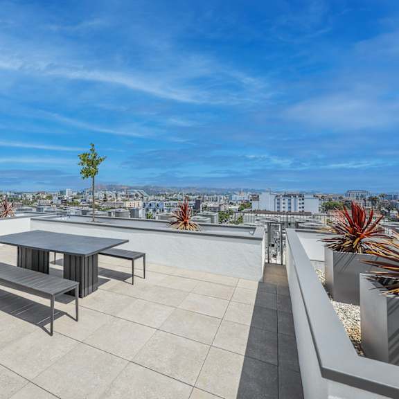 a table and benches are on a rooftop terrace with a view of the city.