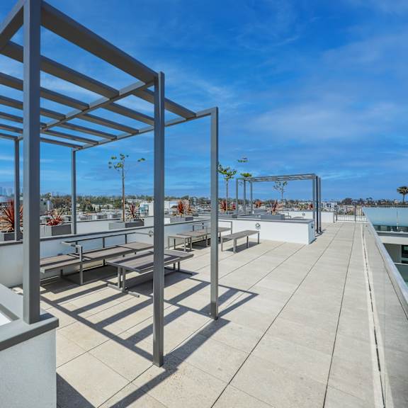 a modern outdoor seating area with a metal pergola and concrete planters.