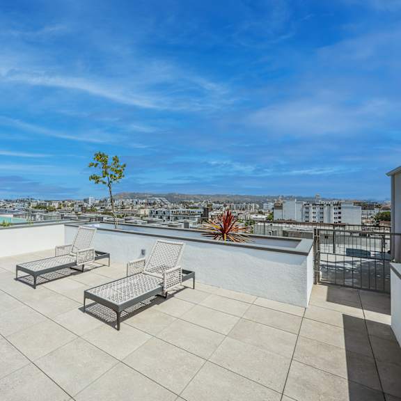 a rooftop patio with a table and chairs overlooking a cityscape.