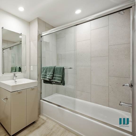 bathroom with shower bath with a glass door and vanity cabinet storage