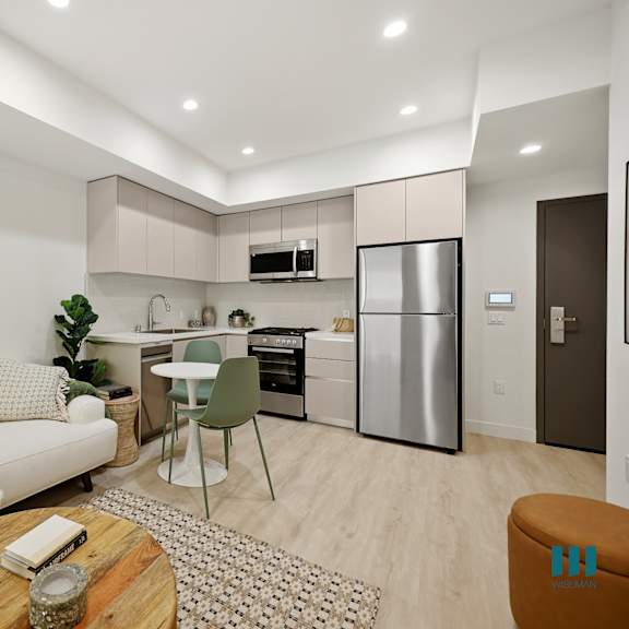 a modern kitchen with a dining table and chairs, a couch, and a painting on the wall.