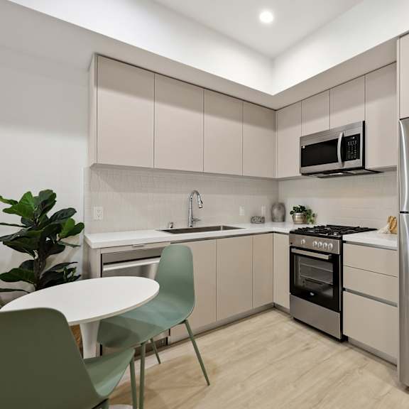a modern kitchen with a stainless steel refrigerator, a microwave above the oven, and a sink with a faucet.