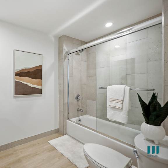 a bathroom with a white toilet, sink, and a painting of a mountain scene on the wall.