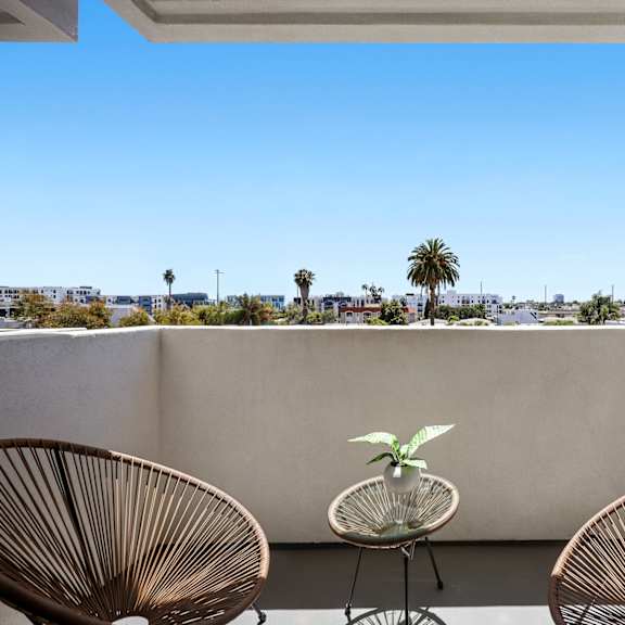two chairs and a table on a balcony with a view of the city.