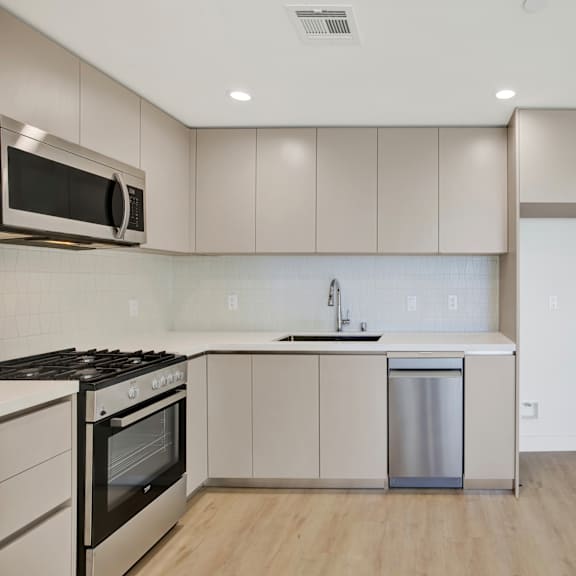 a modern kitchen with a stainless steel dishwasher and wooden flooring.
