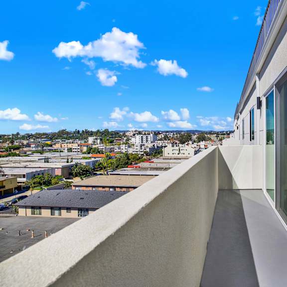 a white building with a balcony overlooking a cityscape.