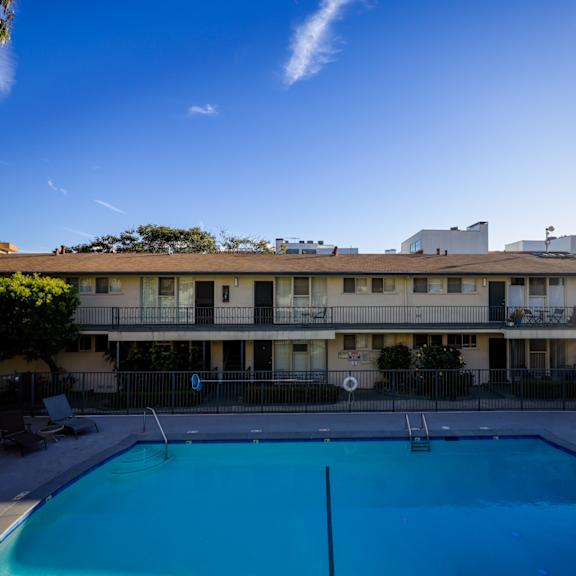 a swimming pool in front of a building with a clear blue sky.