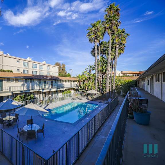 a pool surrounded by palm trees and a fence.